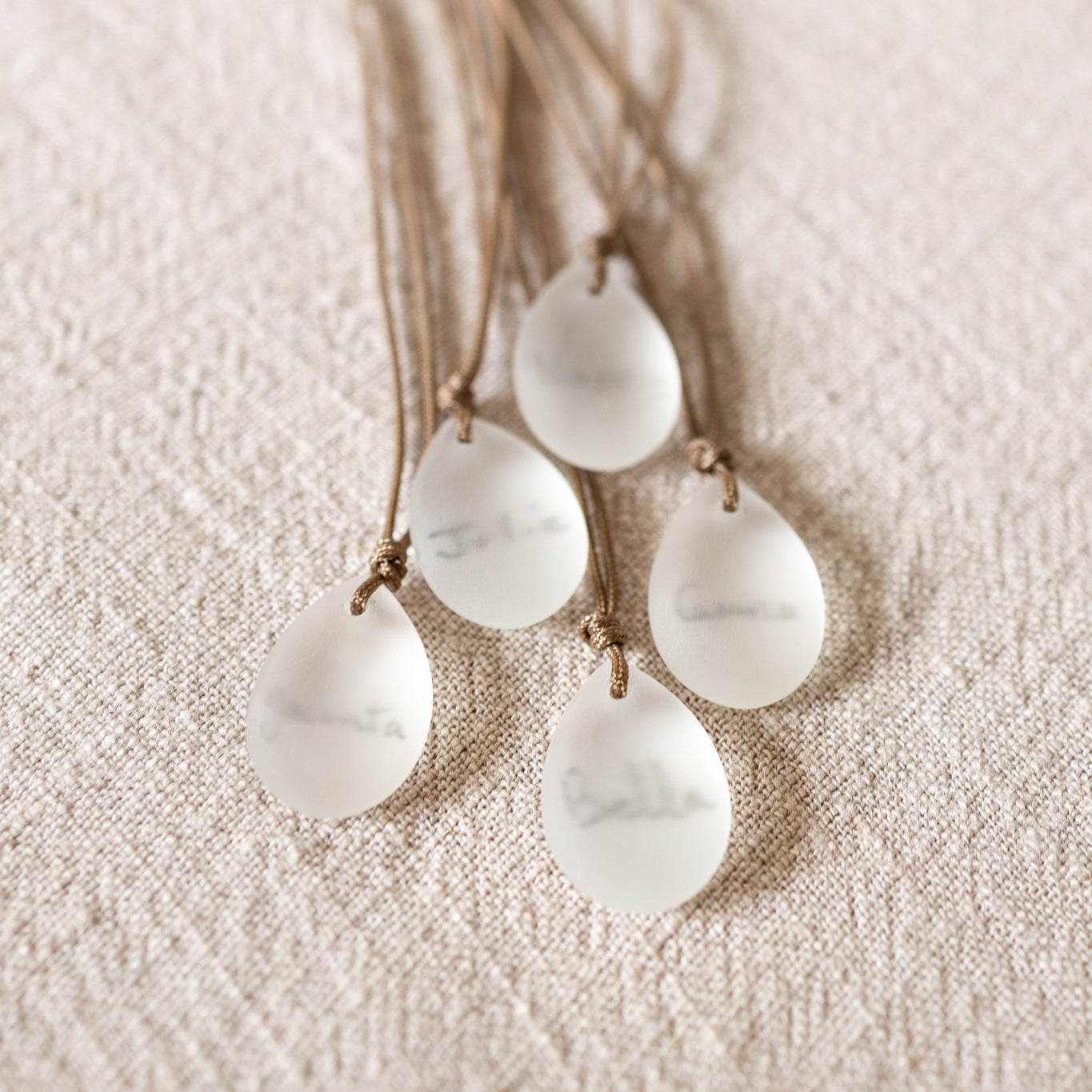 Necklace with teardrop-shaped white stones on a textured beige background
