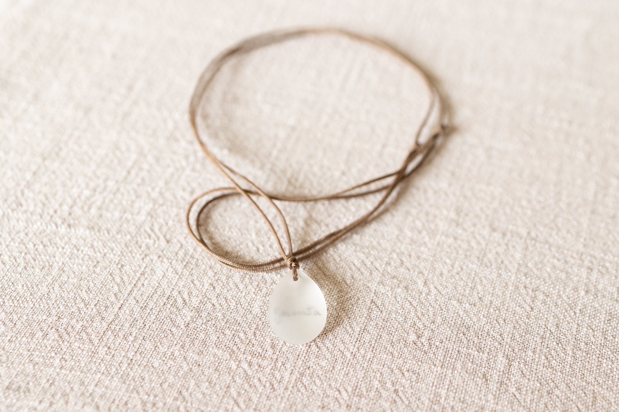 Necklace with a teardrop-shaped pendant on a textured beige surface
